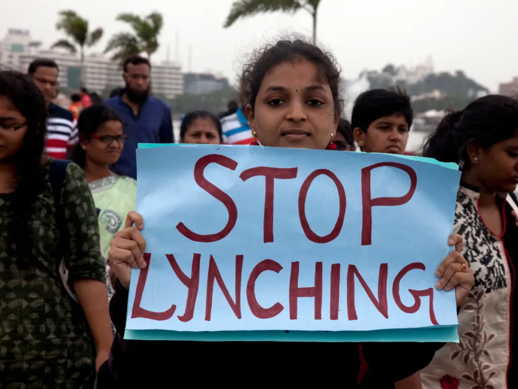 A woman holds a placard and walks to join a protest against a spate of violent attacks across the country targetting the country's Muslim minority, in Hyderabad, India