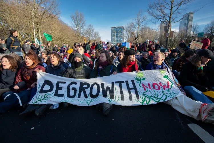 Protesters hold a sign reading “Degrowth Now” after they blocked the A12 highway during an Extinction Rebellion protest on March 11, 2023, in The Hague, Netherlands.